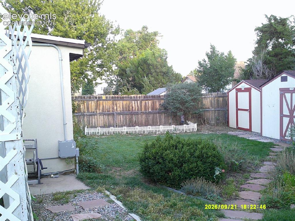 Image 20 of 26: Expansive backyard featuring a privacy fence, two storage sheds, a stone pa