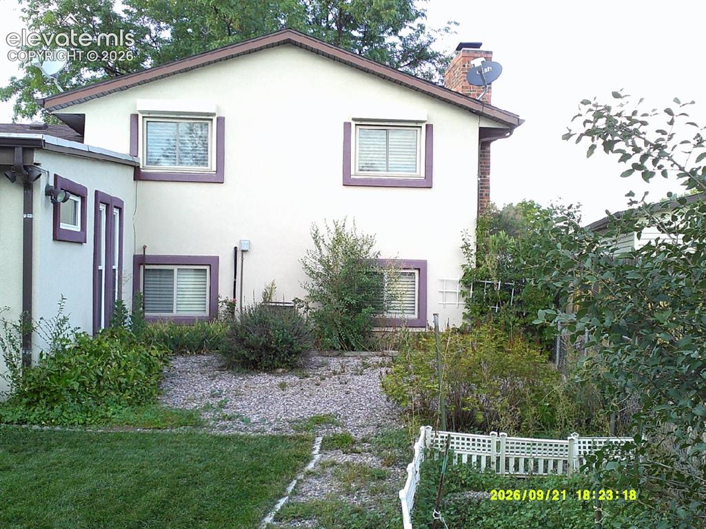 Image 22 of 26: Stucco exterior with contrasting trim, multiple windows with blinds, pitche