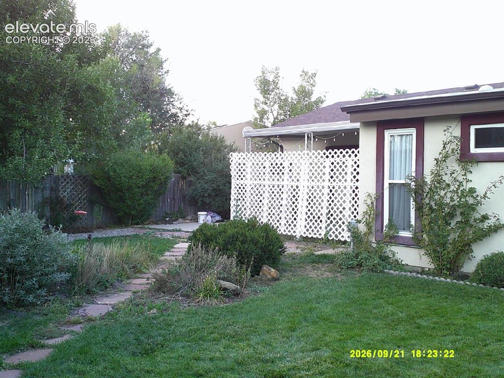 Image 23 of 26: Expansive green lawn, stone-paved pathway, mature trees, white lattice priv