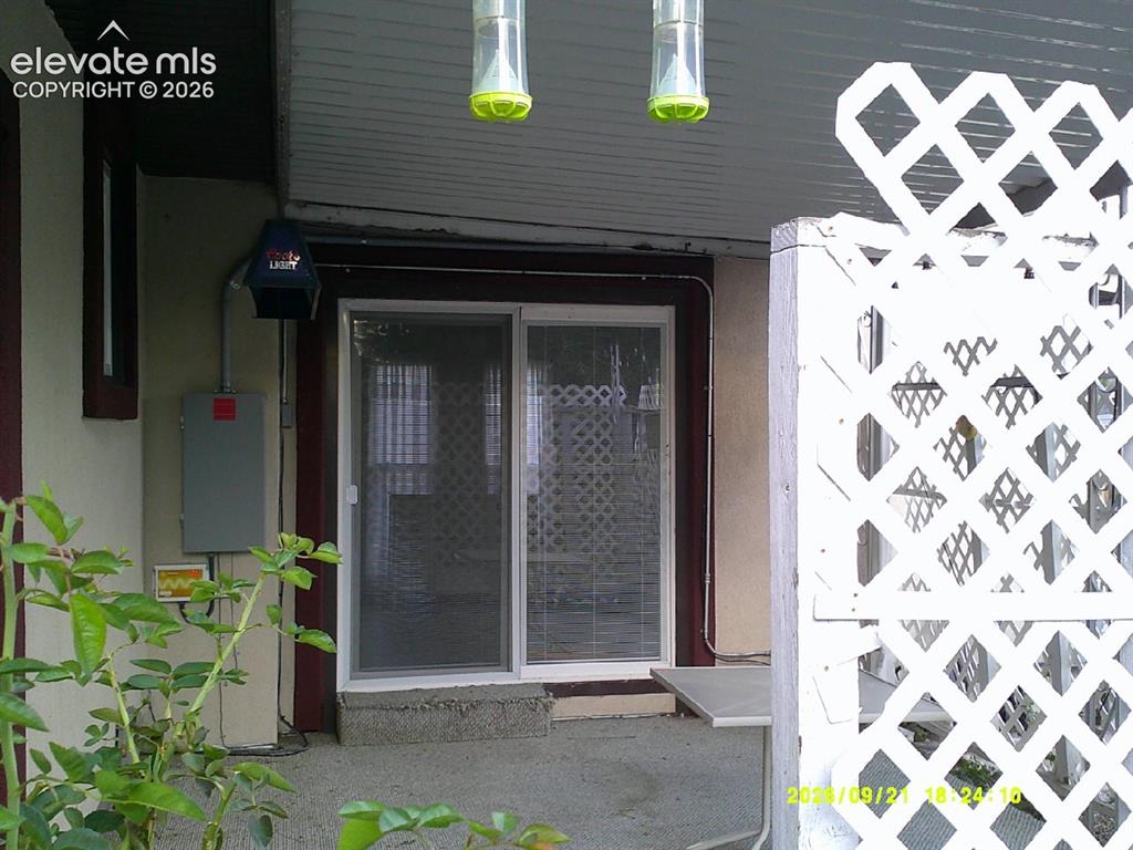 Image 25 of 26: Sliding glass door, concrete patio, white lattice fencing, exterior wall pa