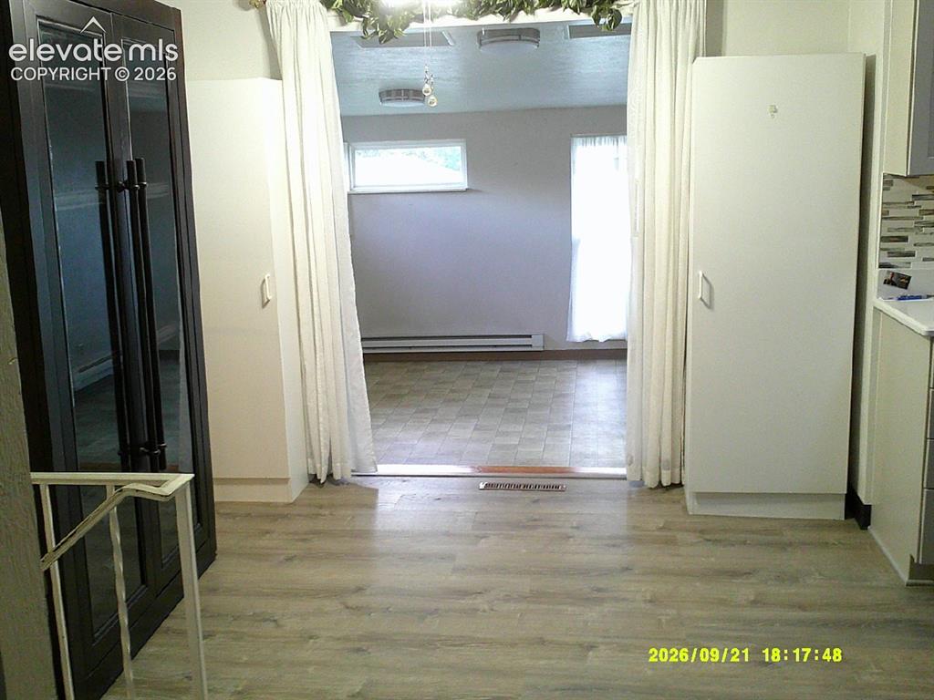 Image 8 of 26: Wood-finish flooring leading to an additional space with tile flooring