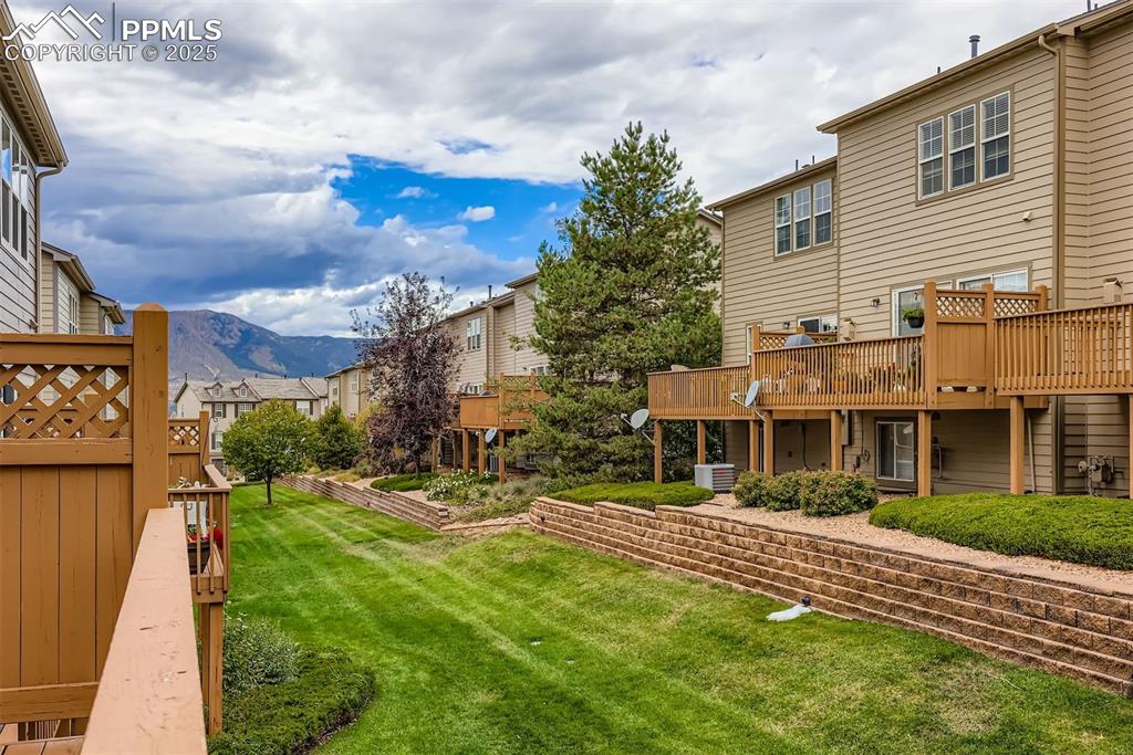 Image 12 of 27: View of grassy yard featuring a deck with mountain view