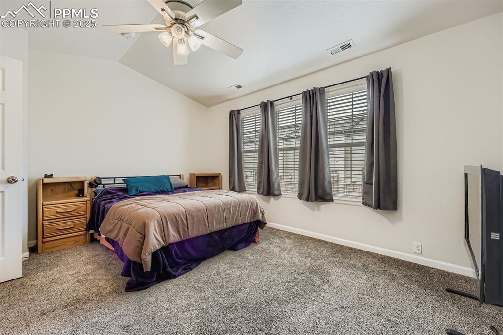 Image 18 of 27: Carpeted bedroom with lofted ceiling and ceiling fan