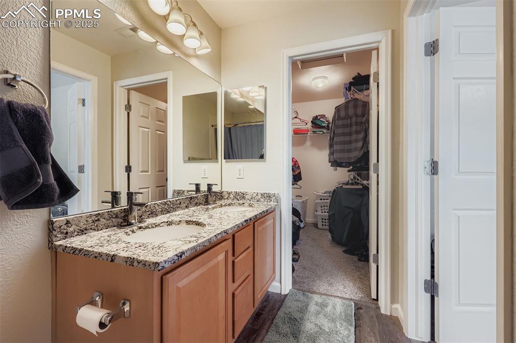 Image 19 of 27: Full bath featuring double vanity, dark wood-style flooring, and a spacious