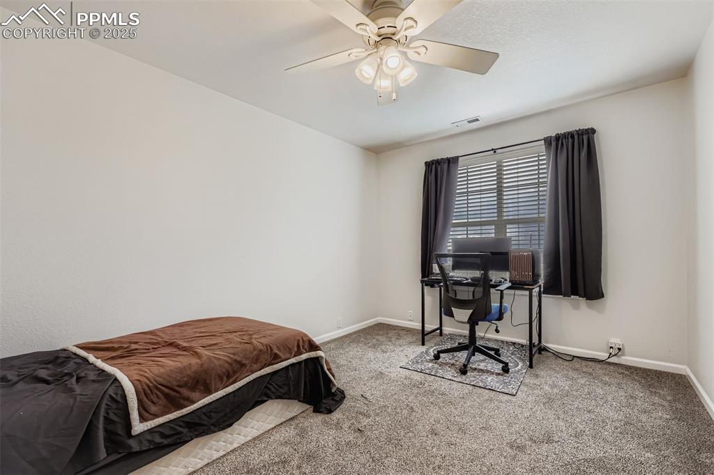Image 21 of 27: Bedroom with a desk, carpet flooring, and a ceiling fan