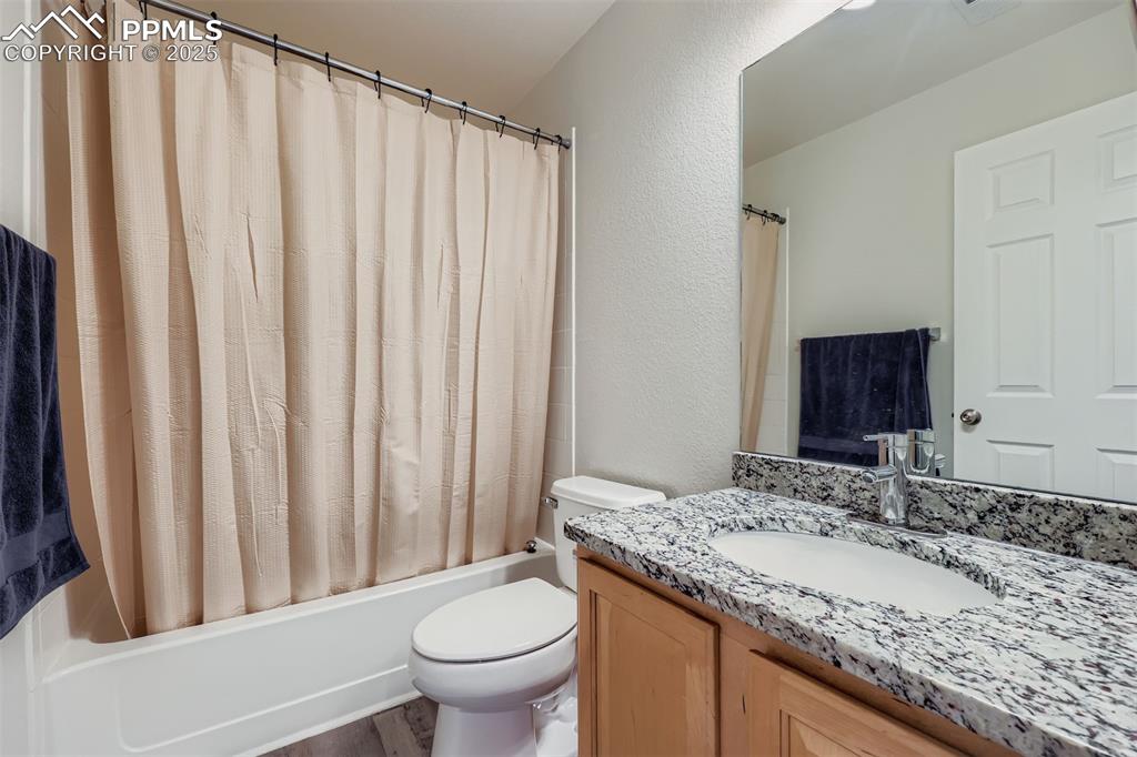 Image 23 of 27: Full bathroom with shower / bath combo, a textured wall, vanity, and dark w