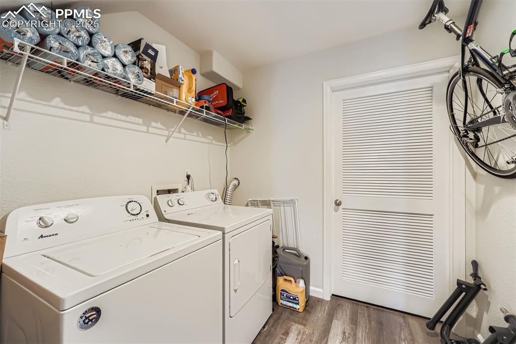 Image 24 of 27: Laundry area with dark wood finished floors and washing machine and clothes