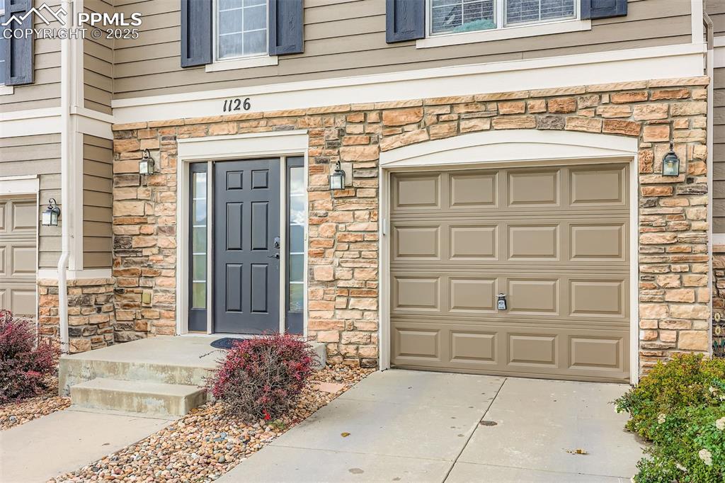 Image 3 of 27: View of exterior entry featuring stone siding and driveway