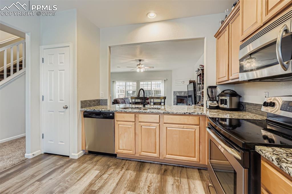 Image 4 of 27: Kitchen with stainless steel appliances, light stone countertops, and light