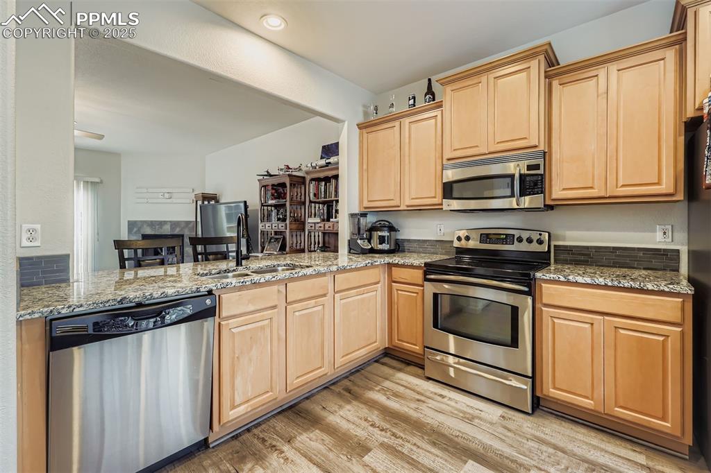 Image 6 of 27: Kitchen with stainless steel appliances, light brown cabinetry, and light s