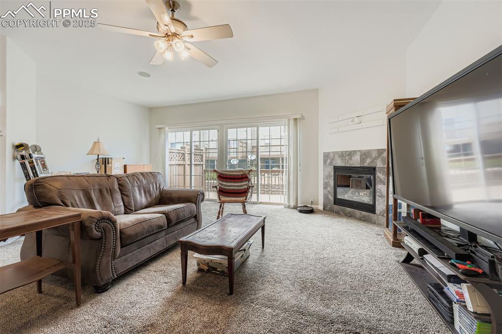 Image 8 of 27: Living area featuring carpet, a high end fireplace, and a ceiling fan