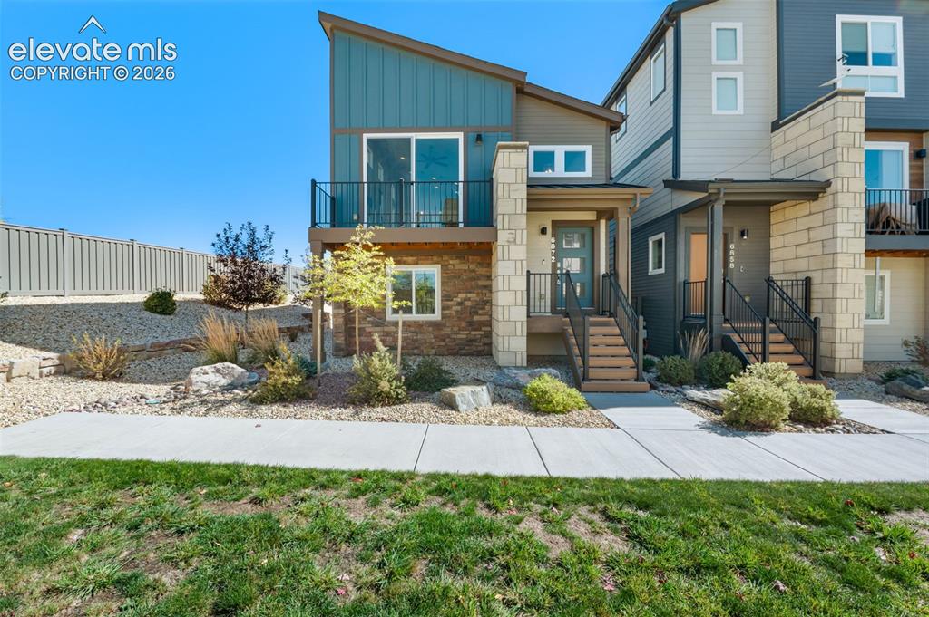 Caption: Modern exterior featuring vertical teal siding, horizontal tan cladding, decorative stone veneer, a 