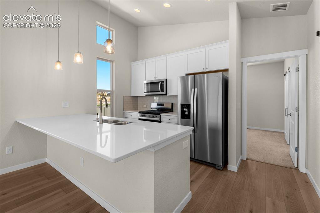 Image 10 of 34: Kitchen featuring white cabinetry, quartz countertops, stainless steel appl