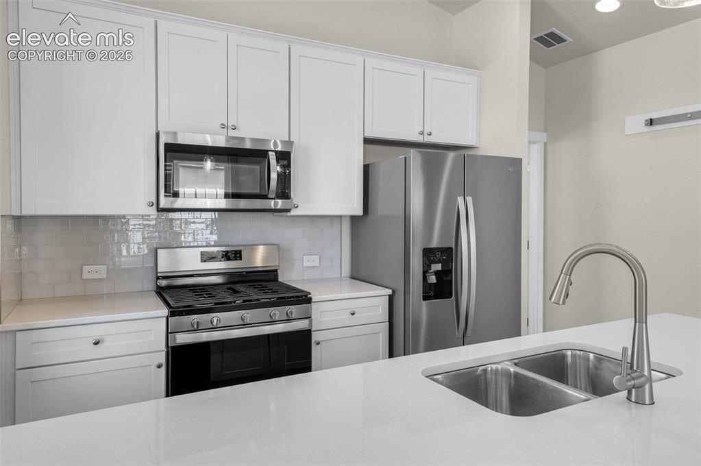 Image 11 of 34: Kitchen featuring white shaker-style cabinetry, stainless steel appliances,