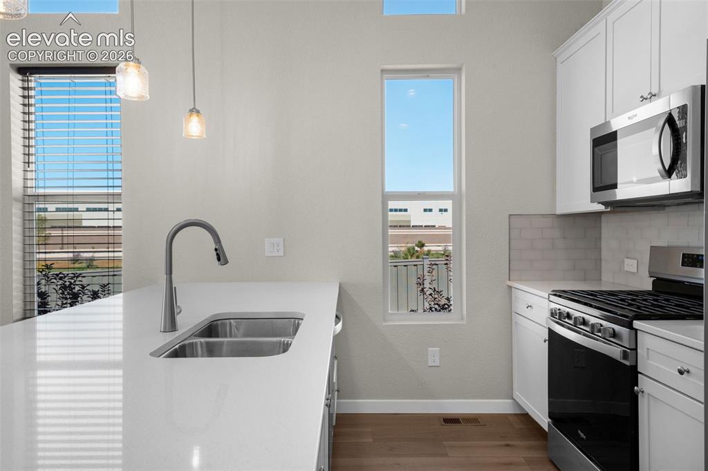Image 12 of 34: Kitchen featuring white cabinetry, quartz countertops, a dual-basin undermo