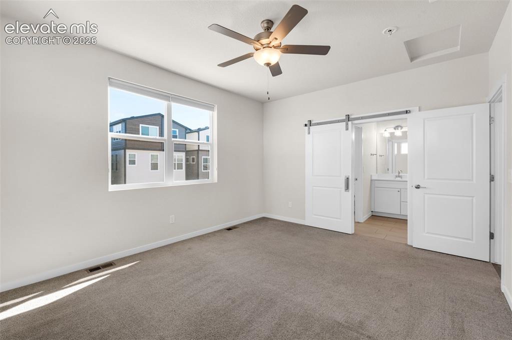 Image 17 of 34: Neutral-toned bedroom featuring carpeted flooring, a ceiling fan with integ