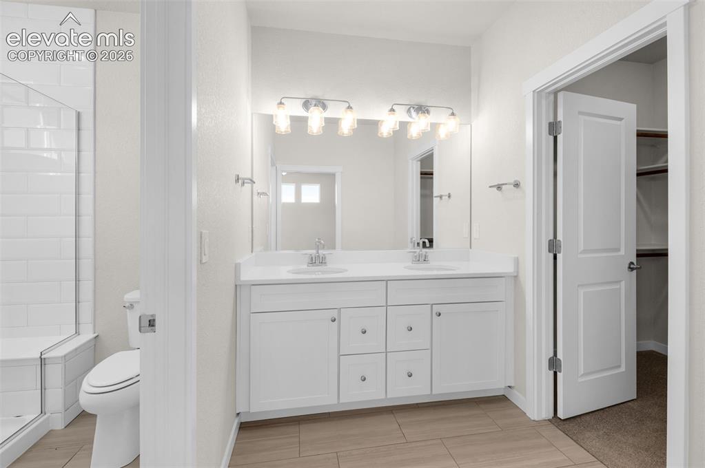 Image 18 of 34: Dual-sink vanity with white cabinetry and solid-surface countertop, full-wi