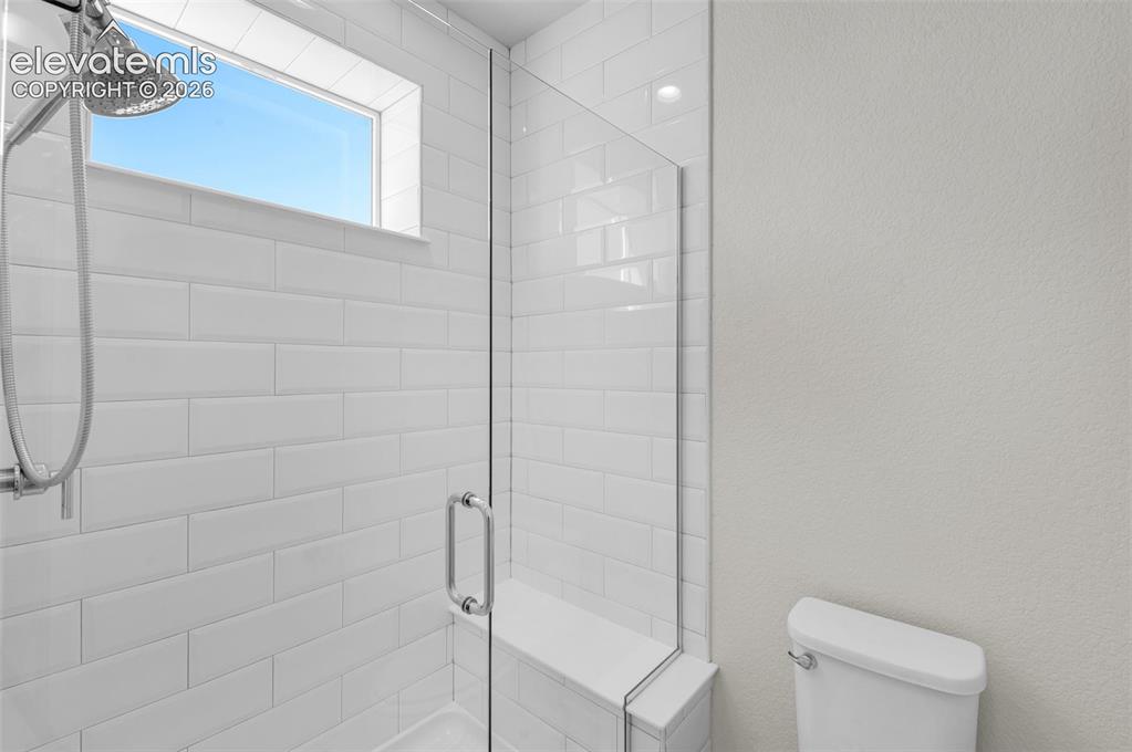 Image 19 of 34: Shower featuring white subway tile, frameless glass enclosure, built-in til