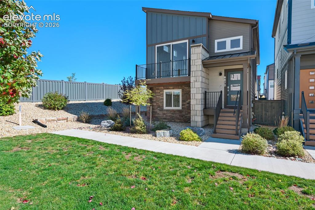 Image 2 of 34: Modern exterior featuring vertical siding, stone veneer accent pillars, a c