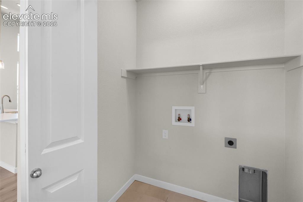Image 20 of 34: Utility area featuring wood-finish flooring, a wall-mounted shelf, and dedi