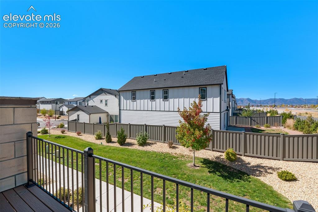 Image 24 of 34: Balcony with dark metal railings, wood-finish decking, and mountain backdro