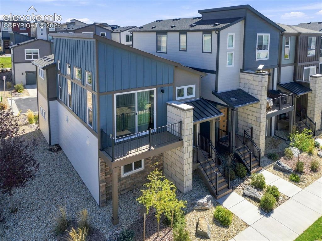 Image 28 of 34: Modern multi-level exterior featuring vertical metal siding, stacked stone 