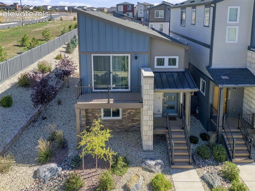 Image 29 of 34: Contemporary multi-level exterior featuring vertical siding, stone veneer a
