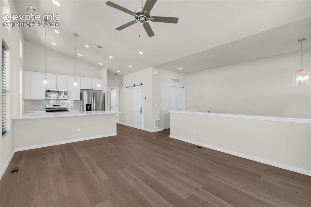 Image 6 of 34: Vaulted ceilings with recessed lighting, wood-finish flooring, white cabine