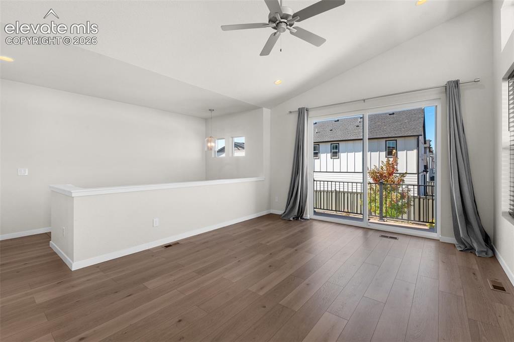 Image 7 of 34: Vaulted ceilings with a ceiling fan, wood-finish flooring, half-wall partit