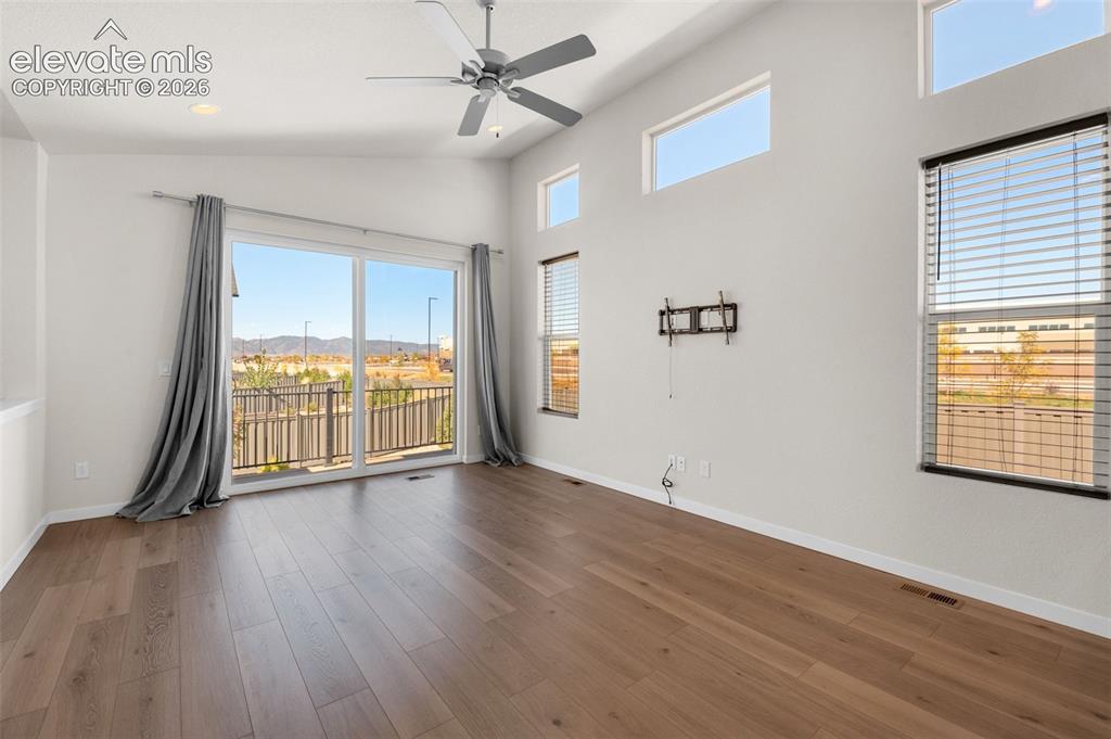 Image 8 of 34: Living area featuring high vaulted ceilings, wood-finish flooring, sliding 