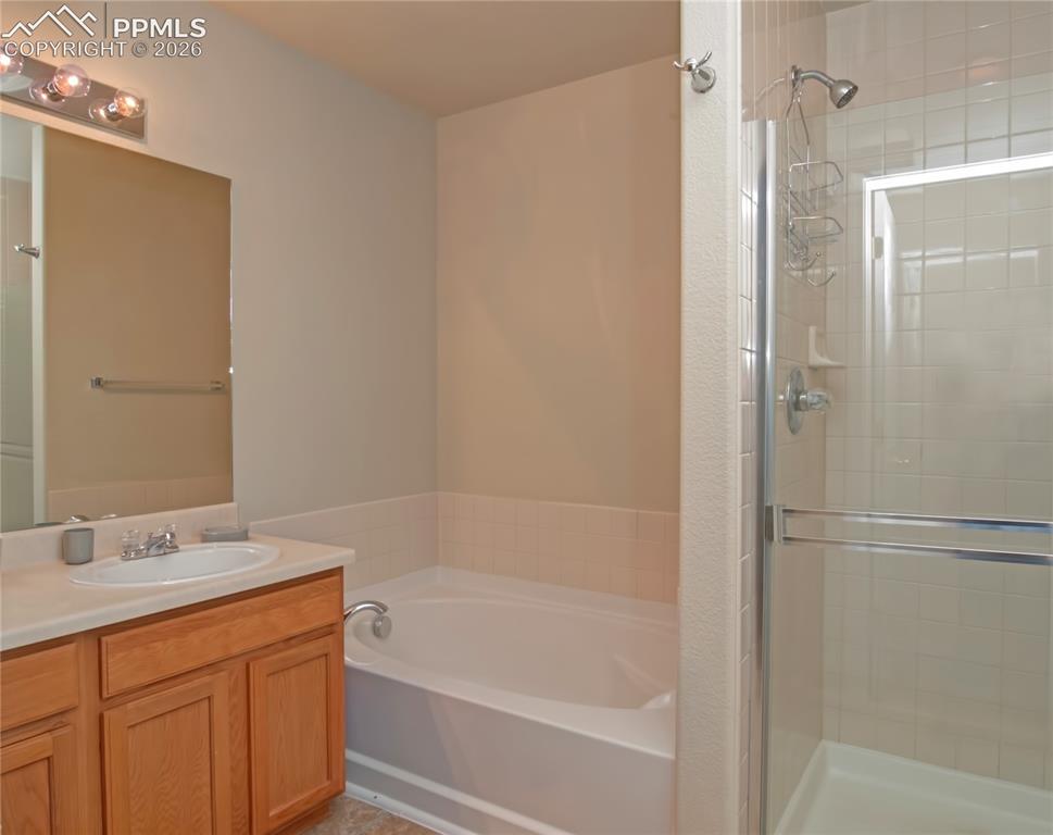 Image 18 of 25: Bathroom with vanity, a stall shower, and a bath
