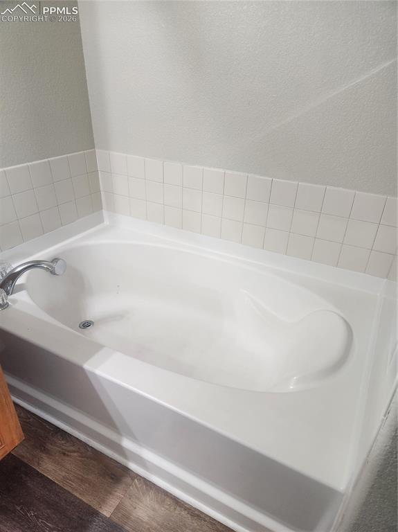 Image 19 of 25: master bath with garden tub, and dark wood-style flooring