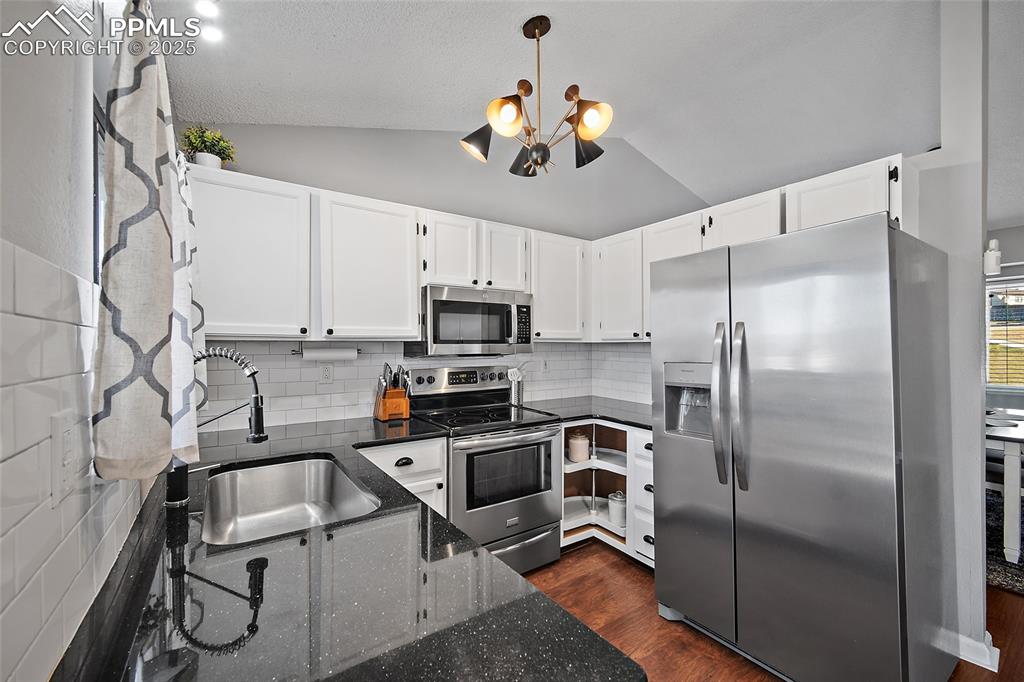Image 12 of 50: Kitchen with stainless steel appliances, white cabinetry, tasteful backspla