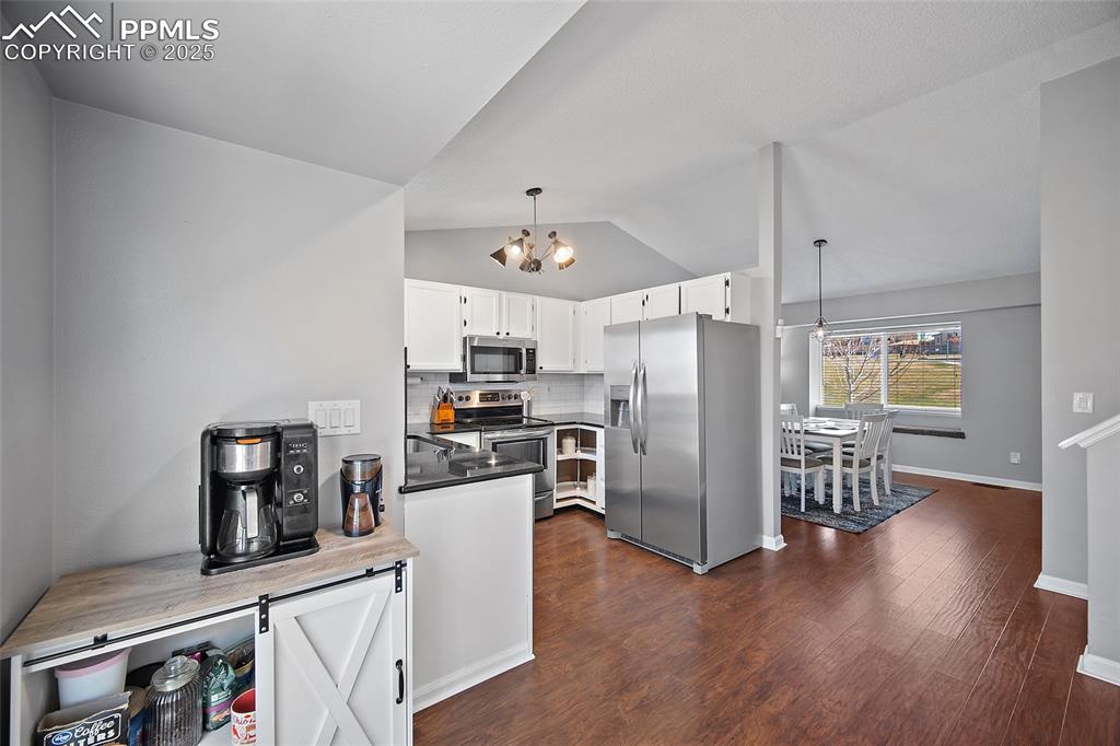 Image 13 of 50: Kitchen featuring decorative backsplash, decorative light fixtures, applian