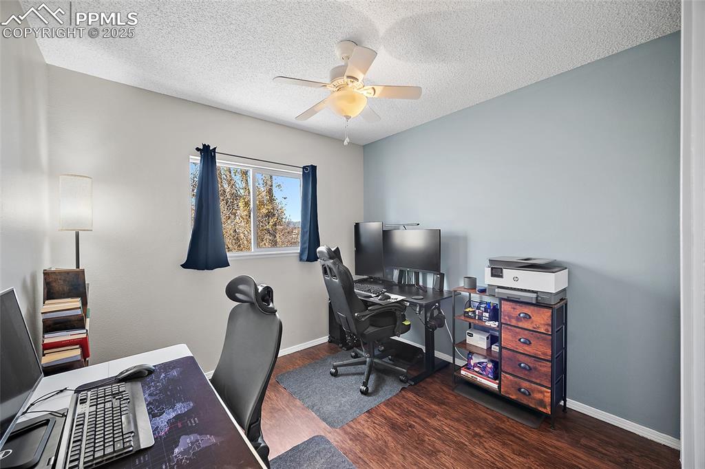 Image 23 of 50: Home office featuring dark wood-style flooring, a textured ceiling, and a c