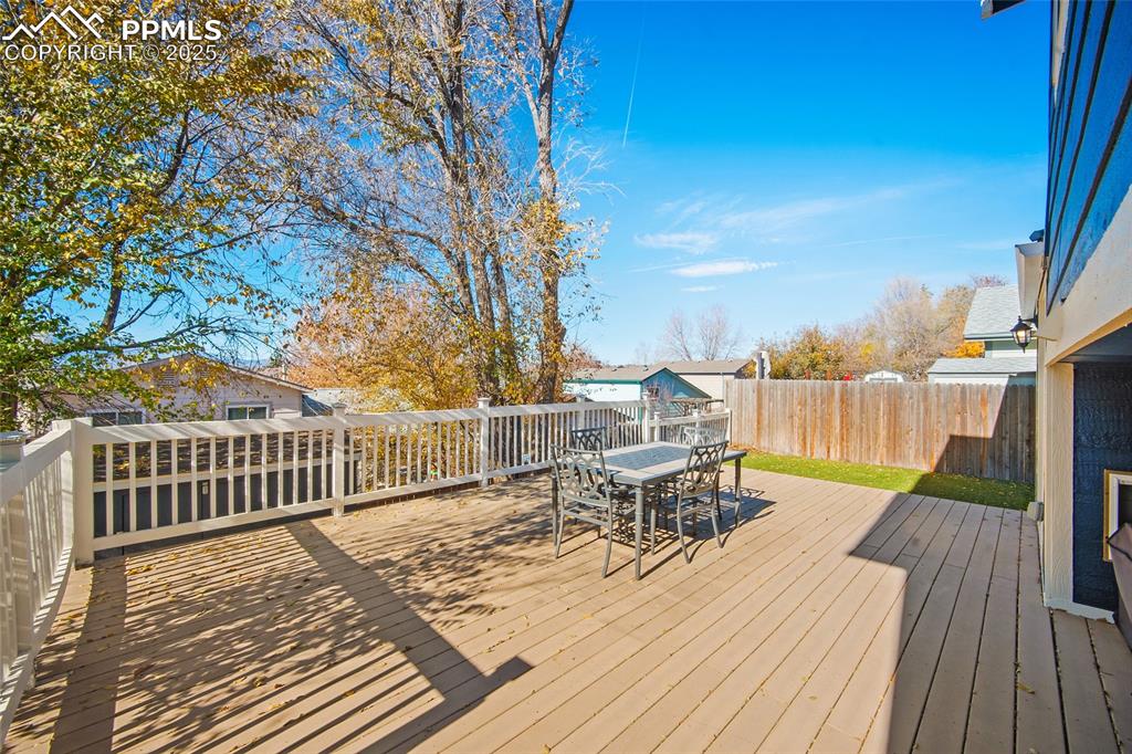 Image 30 of 50: Wooden terrace featuring outdoor dining space and a fenced backyard