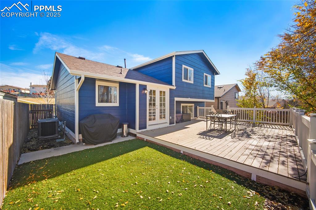 Image 31 of 50: Rear view of house with a yard, a deck, outdoor dining space, and roof with
