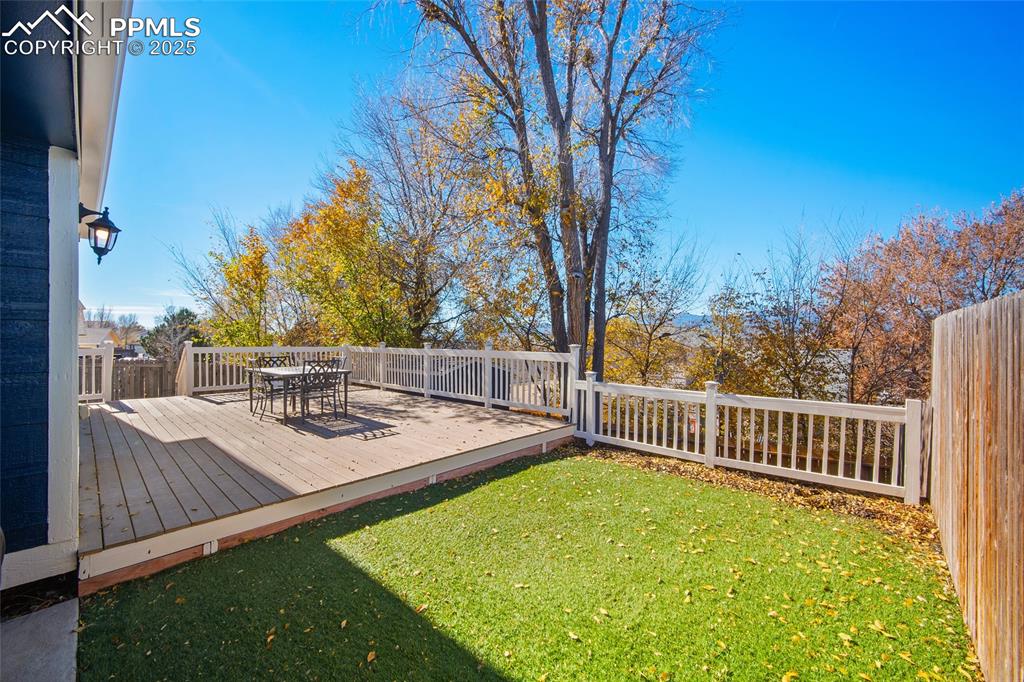 Image 32 of 50: Fenced backyard with a deck and outdoor dining area