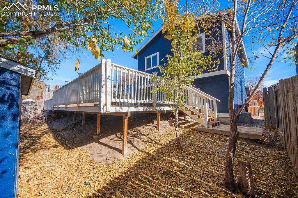Image 34 of 50: Rear view of property featuring a wooden deck, a fenced backyard, and stair