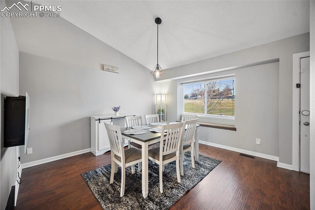 Image 4 of 50: Dining room featuring vaulted ceiling and dark wood-type flooring