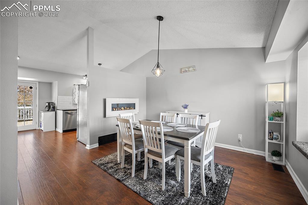 Image 6 of 50: Dining area featuring lofted ceiling, dark wood finished floors, and a text