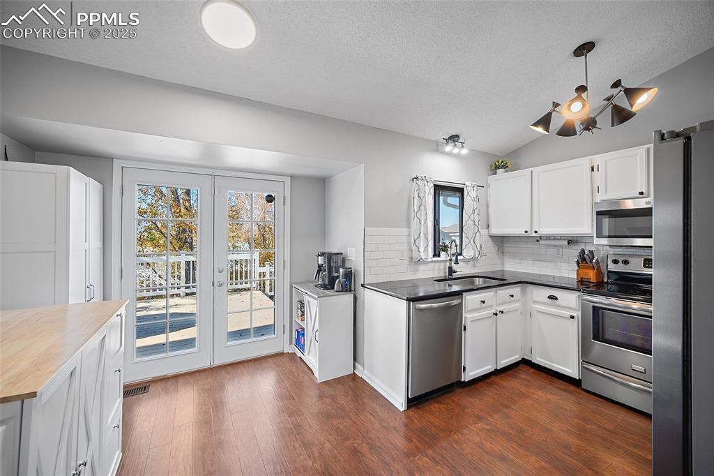 Image 7 of 50: Kitchen with stainless steel appliances, a textured ceiling, white cabinetr