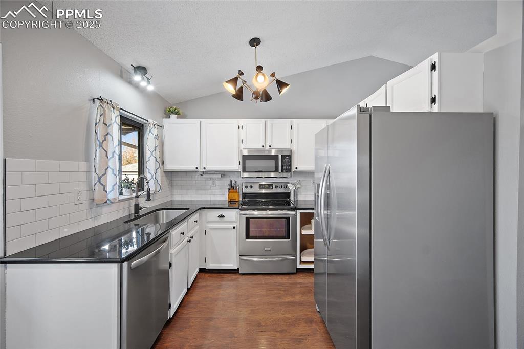 Image 8 of 50: Kitchen featuring appliances with stainless steel finishes, dark wood finis