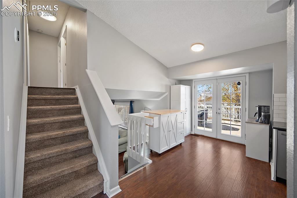 Image 9 of 50: Stairs featuring wood finished floors, lofted ceiling, and a textured ceili