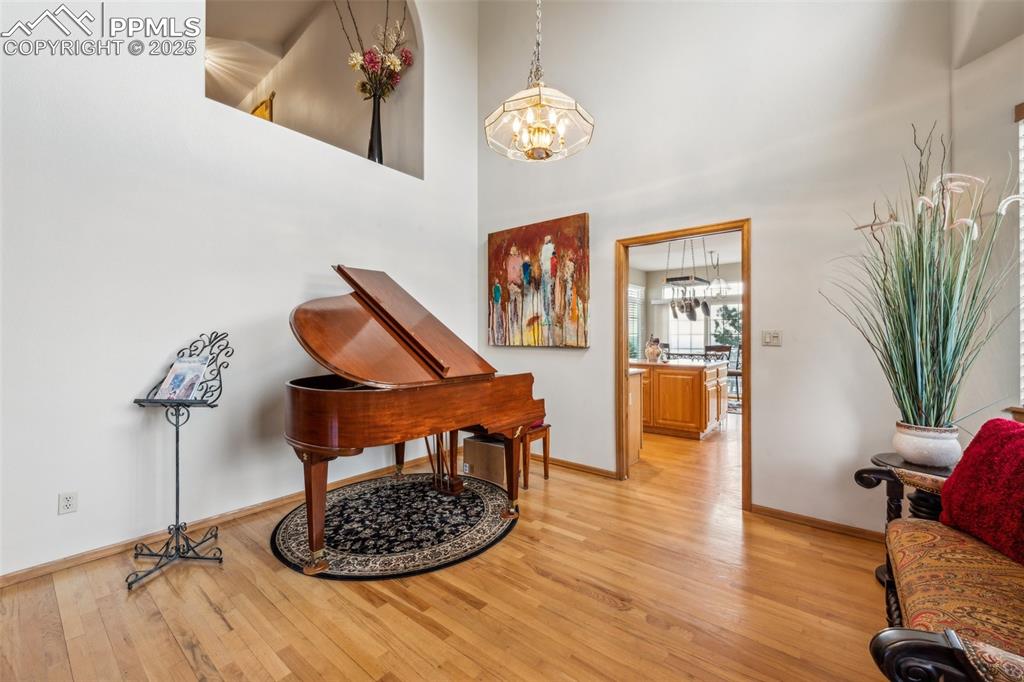Image 11 of 43: Sitting room featuring light wood-style floors, a high ceiling, and a chand