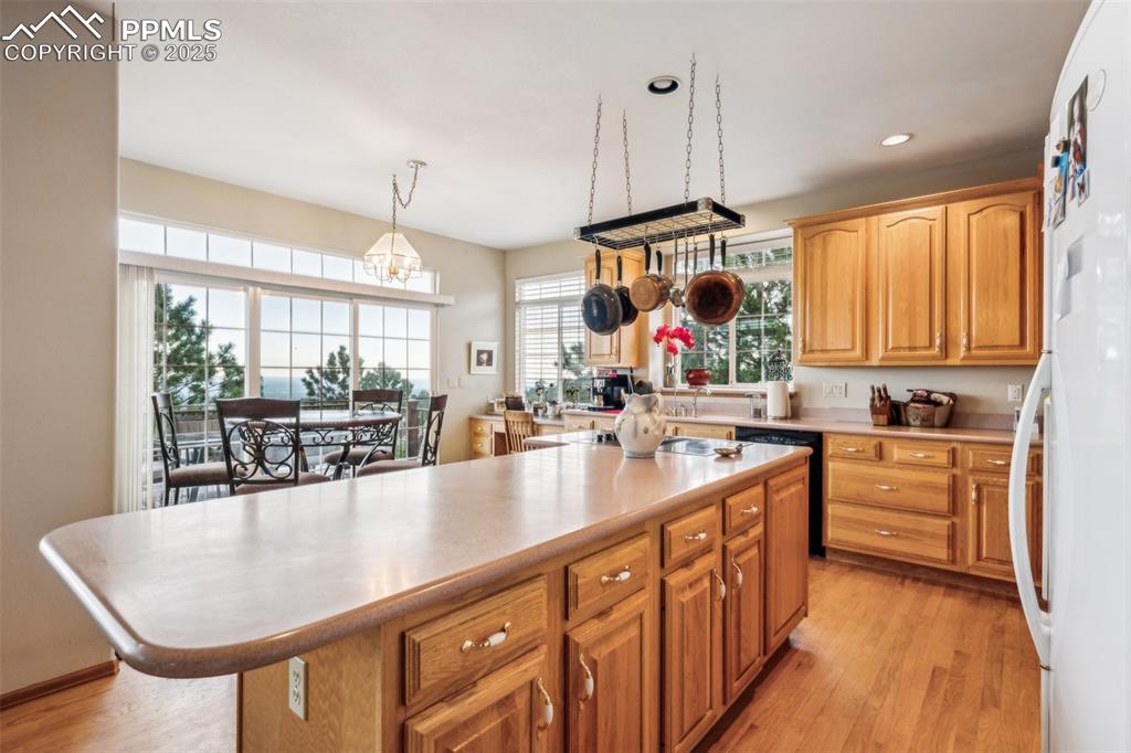 Image 15 of 43: Kitchen with light countertops, freestanding refrigerator, light wood-style