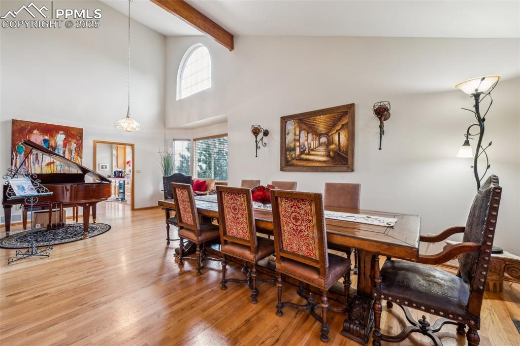 Image 8 of 43: Dining room with high vaulted ceiling, light wood-style floors, and beam ce