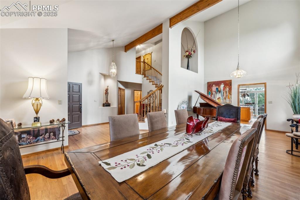 Image 9 of 43: Dining space with high vaulted ceiling, stairway, beamed ceiling, wood fini