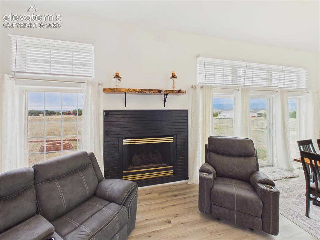 Image 19 of 50: Floor-to-ceiling windows and a striking gas fireplace create a warm, inviti