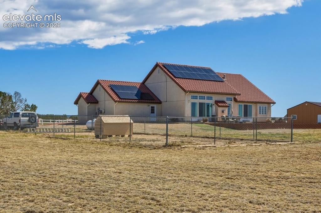 Image 43 of 50: Rear view of the home showcasing solar panels, outdoor living space, and a
